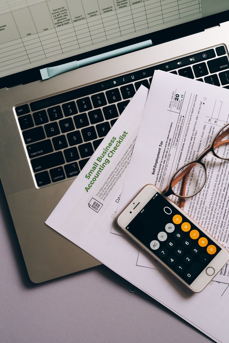 Phone and printed documents beside a laptop on a desk